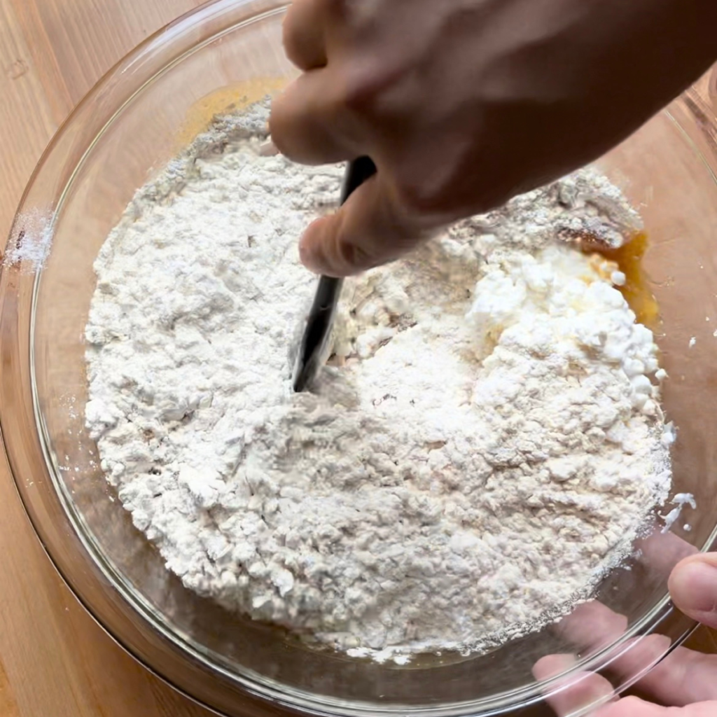 Dry ingredients added to wet ingredients for cottage cheese muffins for toddlers in glass bowl 