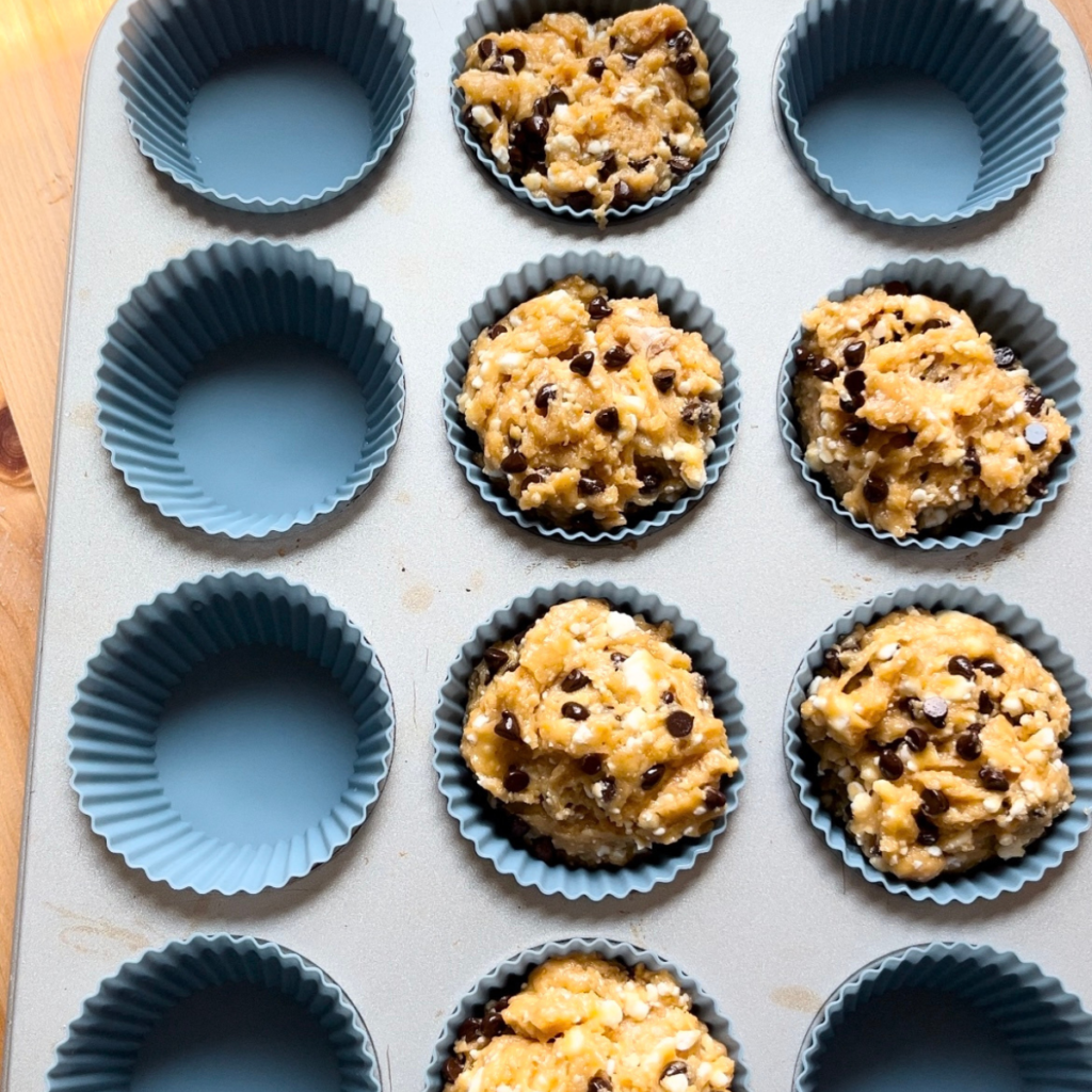 muffin batter being scooped into muffin pan 
