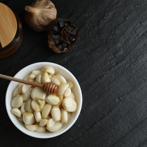peeled garlic cloves sitting in white bowl on black surface