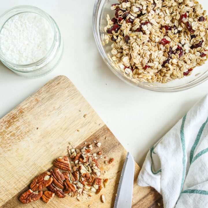 Flat lay of granola, milk, and nuts on a wooden board, promoting healthy breakfast.