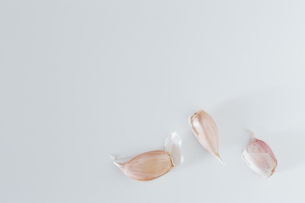 Three garlic cloves on a clean white background, perfect for culinary or health concepts.