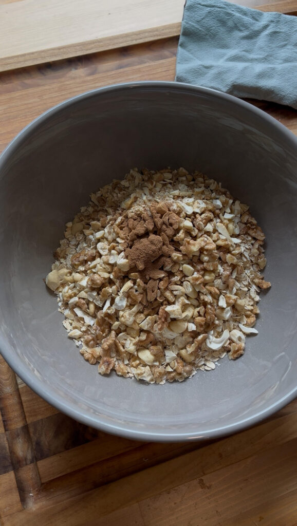 Gray bowl of rolled organic oats with chopped nuts and cinnamon