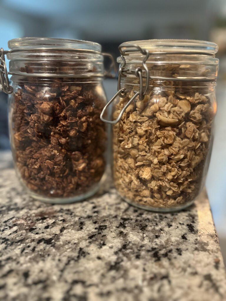 Chocolate and regular granola in a glass container on counter