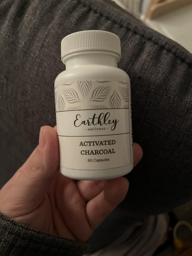 activated charcoal in white bottle being held in-front of blue chair