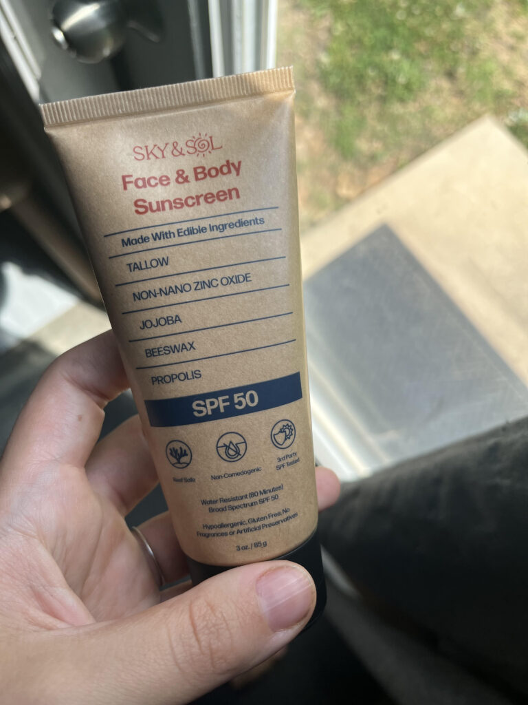 Non toxic skincare made with tallow in a hand infront of outside door