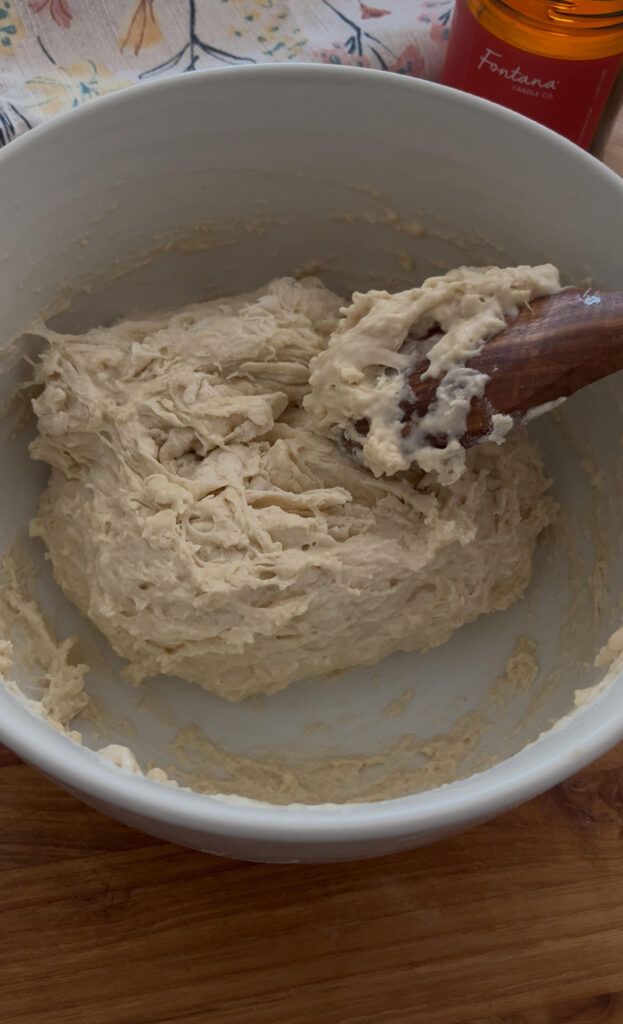 Mixing dough for Easy Yeast Artisan Bread in a white bowl with a wooden spoon
